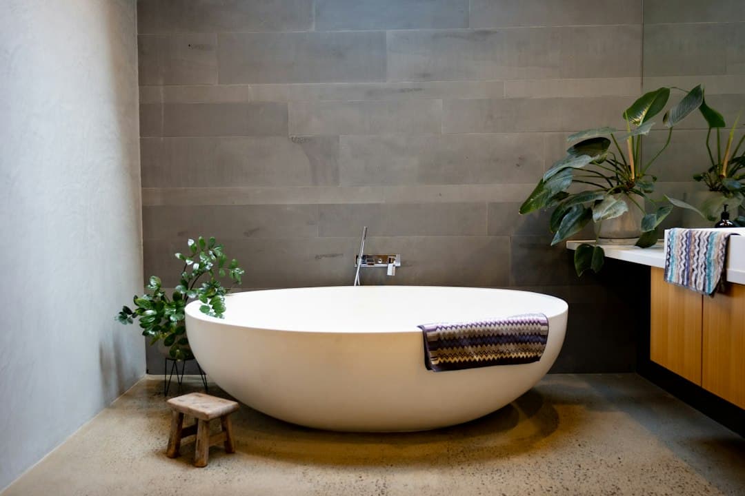 a bathtub in a bathroom with a plant in the corner — Photo by Rebecca Chandler on Unsplash