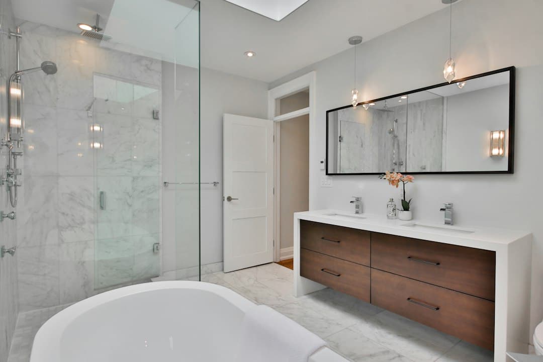 a bathroom with a large white bathtub next to a walk in shower — Photo by Lotus Design N Print on Unsplash