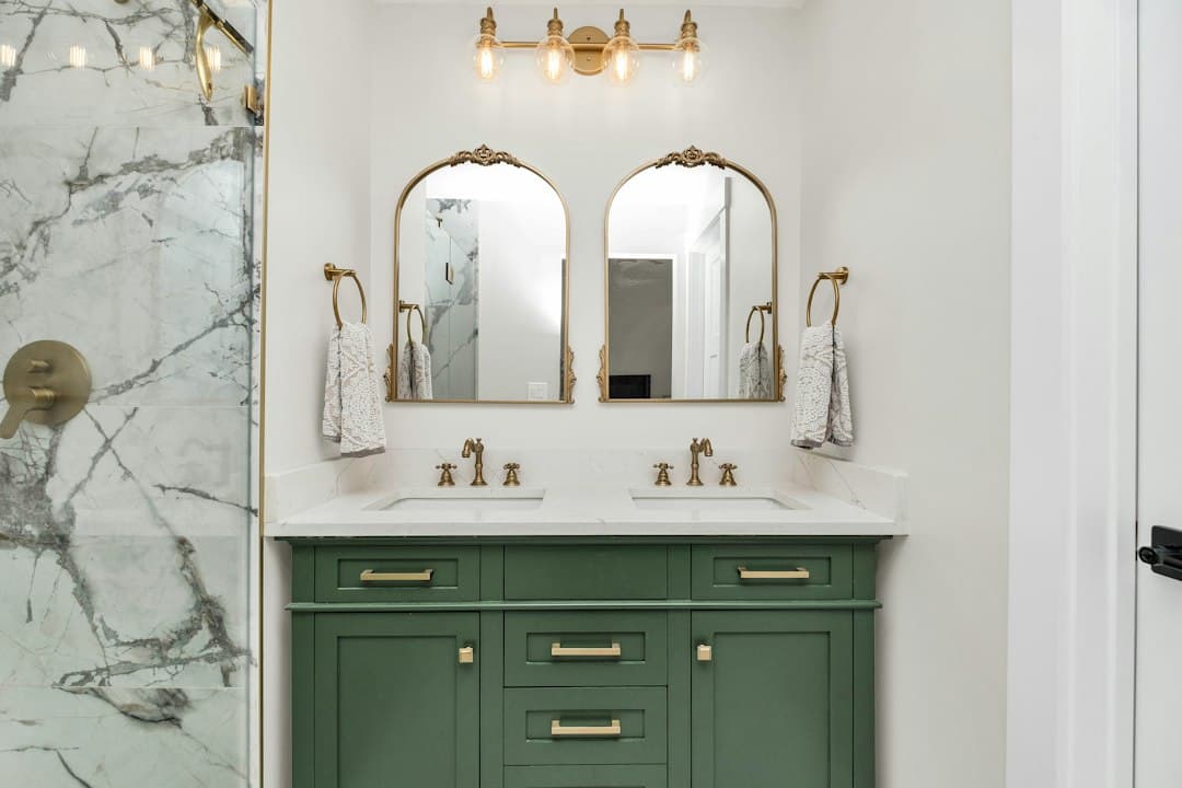 a bathroom with marble counter tops and green cabinets — Photo by Zac Gudakov on Unsplash