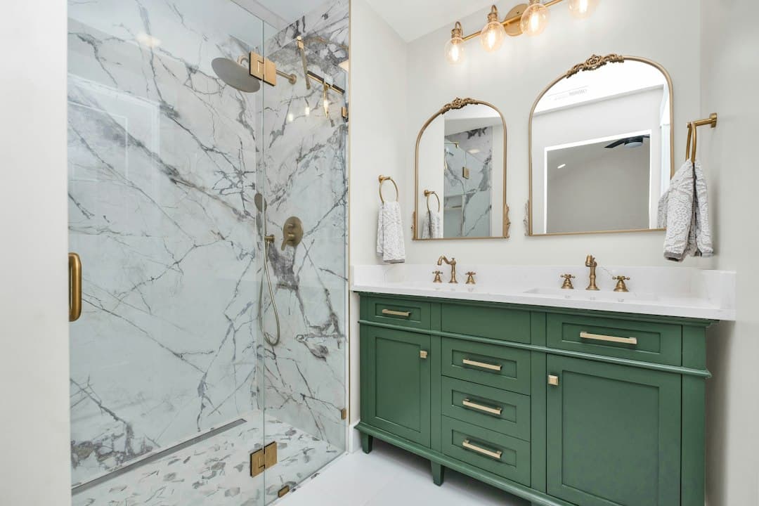a bathroom with green cabinets and a marble shower — Photo by Zac Gudakov on Unsplash