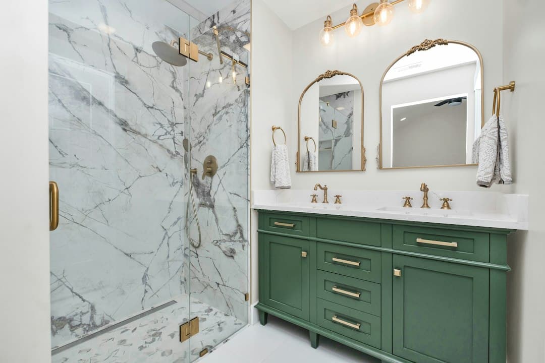 a bathroom with green cabinets and a marble shower — Photo by Zac Gudakov on Unsplash