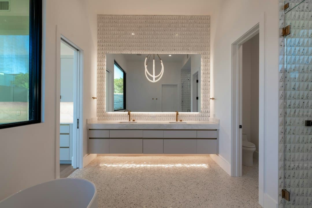 Elegant modern bathroom with large illuminated mirror and double vanity — Photo by Salvo Media LLC on Unsplash
