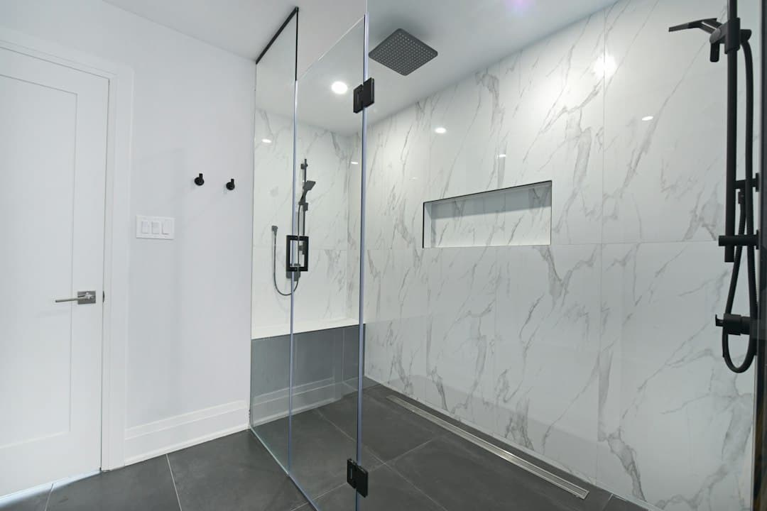 Modern bathroom with glass-enclosed shower and marble walls — Photo by Smart Renovations on Unsplash