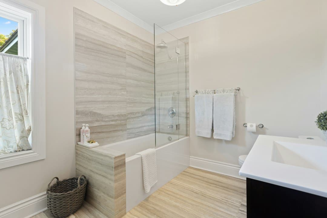 a bathroom with a tub, sink, and mirror — Photo by Point3D Commercial Imaging Ltd. on Unsplash