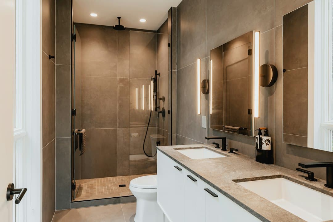 a bathroom with two sinks, a toilet and a shower — Photo by Clay Banks on Unsplash