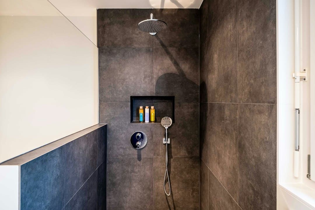stainless steel shower head on white ceramic wall tiles — Photo by immo RENOVATION on Unsplash