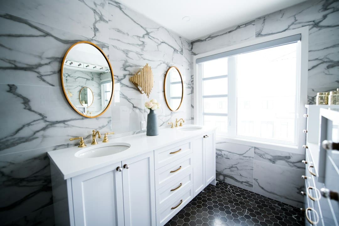 a bathroom with two sinks and a large mirror — Photo by Christian Mackie on Unsplash